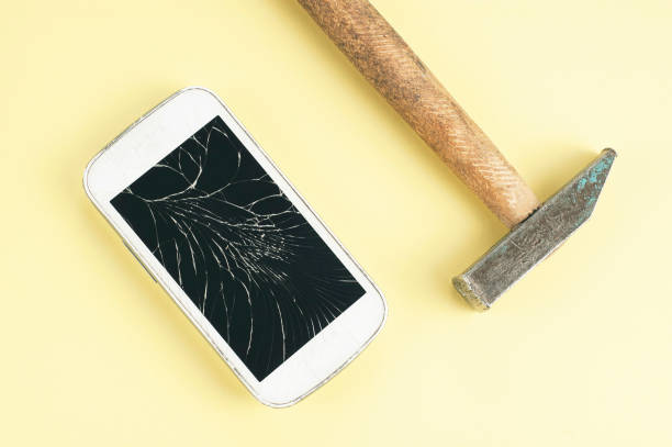 istock A cell phone with cracked screen and a hammer on brown background 1321261626