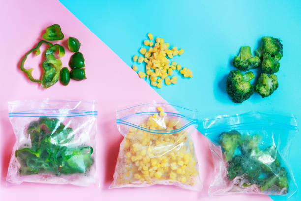 istock Three packets of frozen scattered vegetables on blue and pink background. 1321261764