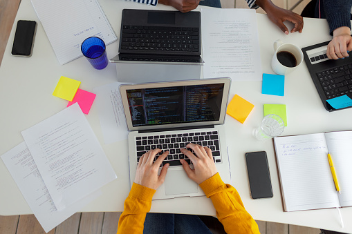 Close-up of businesswoman coding on laptop at home office.