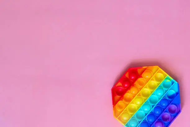 Photo of the rainbow-colored pop toy lies on the background. space for text