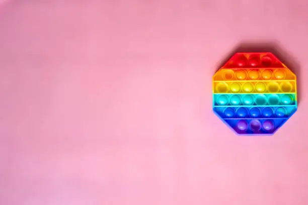 Photo of the rainbow-colored pop toy lies on the background. space for text