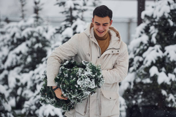 istock Young handsome man carrying fresh cutted fir tree outdoors 1321264443