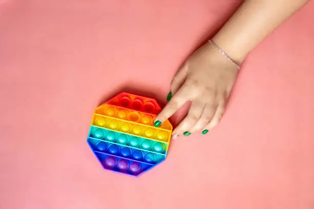 Photo of the rainbow-colored pop toy lies on the background. space for text