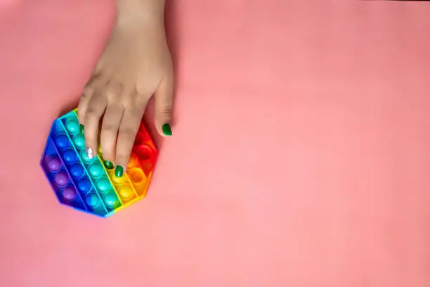 Photo of the rainbow-colored pop toy lies on the background. space for text