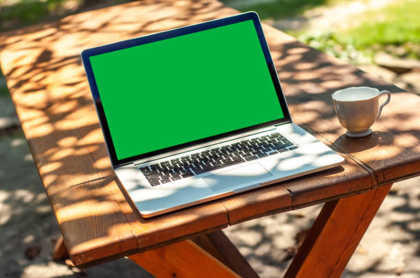 istock View on a laptop pc with a green screen and a coffee mug on a table in the garden 1321265675