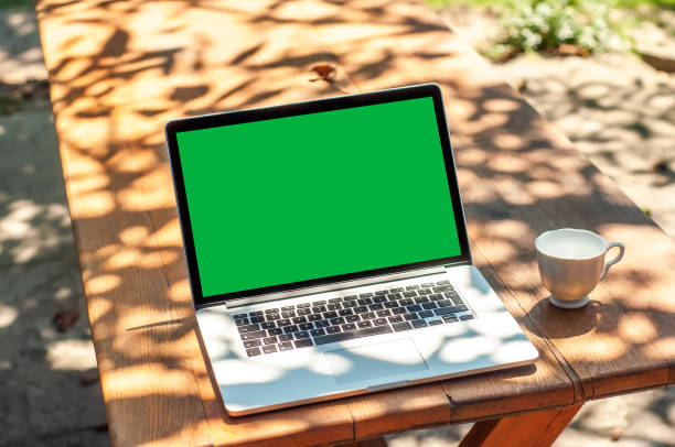 istock View on a laptop pc with a green screen and a coffee mug on a table in the garden 1321265683