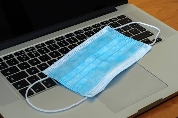 istock View on a medical mask on an open laptop pc. 1321266512