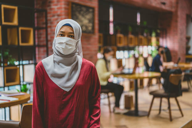 istock Beautiful Asian modern Muslim businesswoman wearing protective face mask in a co-working space 1321267708