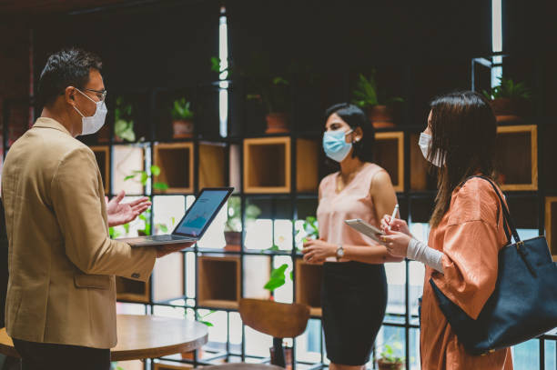 istock Three Asian business coworkers wearing protective face mask while working on laptop at co-working space 1321267717