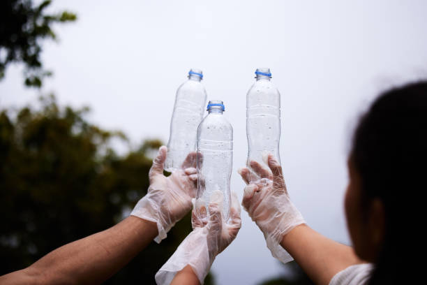 istock Shot of people holding up three empty plastic bottles with a sky background 1321269811