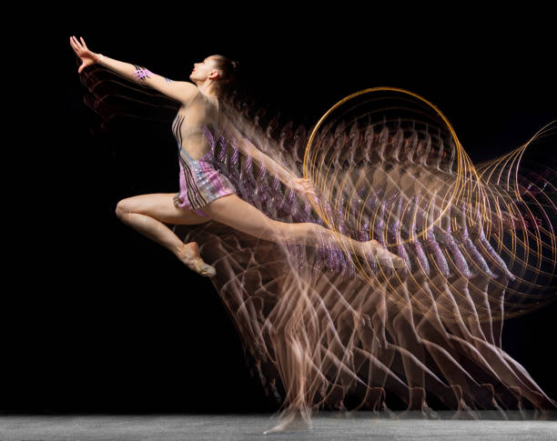 retrato de joven gimnasta rítmica en movimiento y acción aislada en luz mixta sobre fondo oscuro. - stroboscopic image fotografías e imágenes de stock