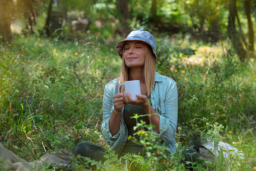 Beautiful Woman Drinking Tea and Chilling in the Forest. Vacation Time. Peaceful Time. Blond Female is Having a Break. Relax the Mind.