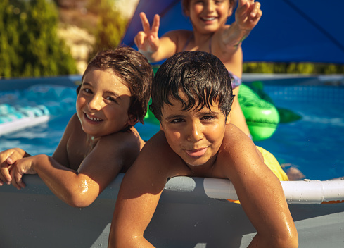 Portrait of a Three Happy Kids Having Fun in the Pool. Big Family Enjoying Summer Holidays on the Beach Resort in the Water Park