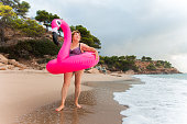 Happy senior woman on the beach with inflatable flamingo ring