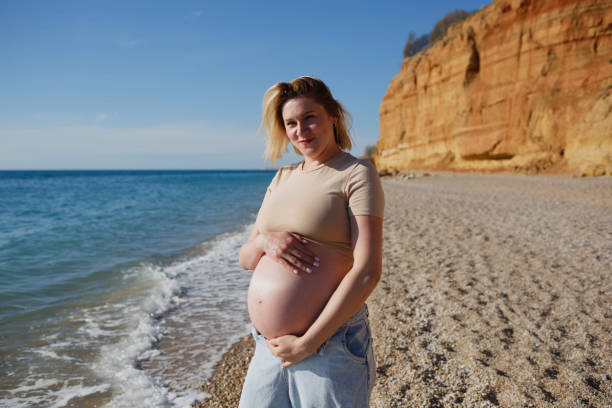 istock a pregnant woman standing on the seashore 1321276338