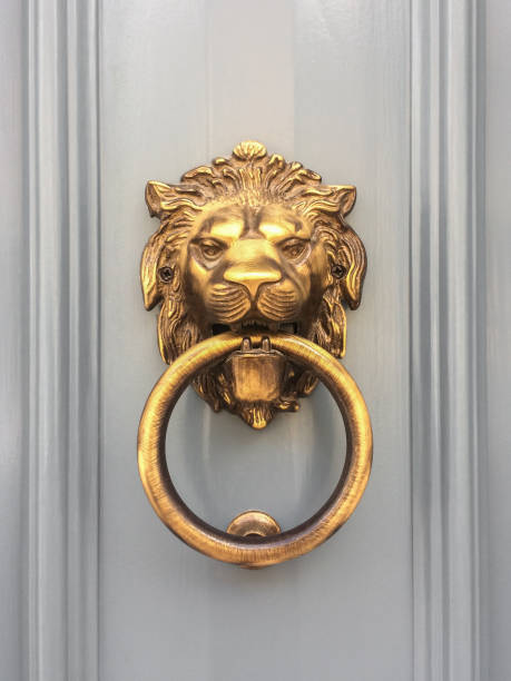 golpeador de puerta de cabeza de león de oro con el anillo en la boca en la entrada de una casa, malta. picaporte tradicional italiano. - aldaba fotografías e imágenes de stock