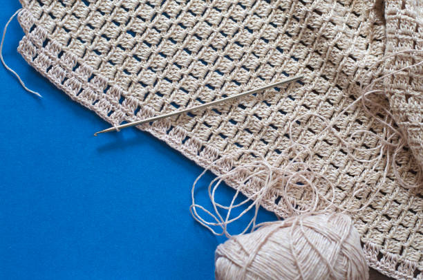 Crochet with beige cotton threads on a blue background. Simple crochet pattern.