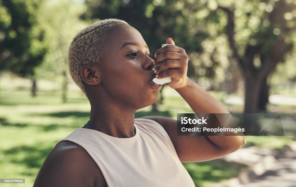 Shot of a young woman taking a break during a workout to use her asthma pump My chest is feeling so tight Asthmatic Stock Photo