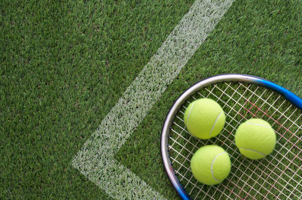 Tennis balls with racket on court stock photo