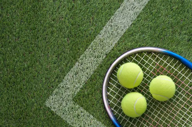 Tennis racket with balls on grass court