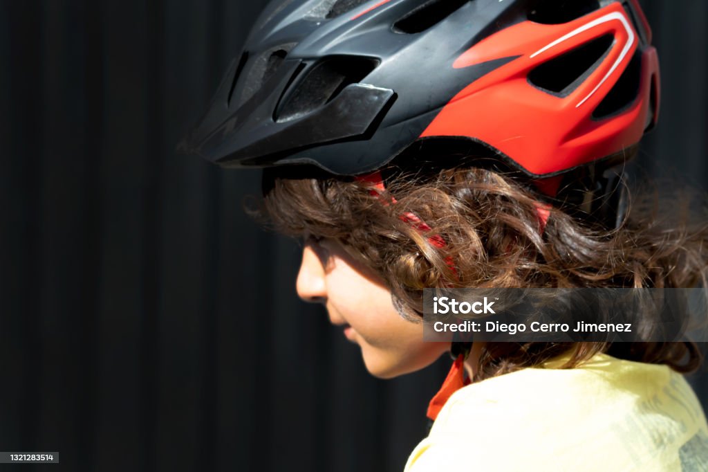 Profile Photo Of A Little Boy With Long Hair Wearing A Safety Helmet Riding  A Bike Black Background Copy Space Stock Photo - Download Image Now - iStock
