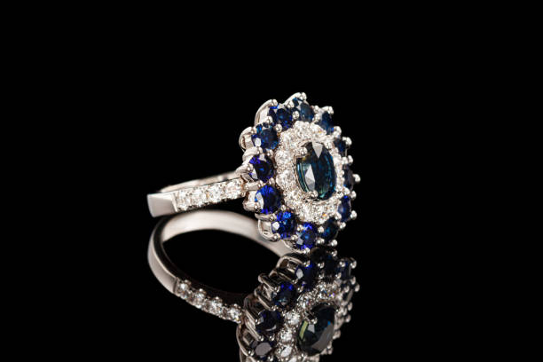 istock Beautiful ring with sapphires and diamonds in gold on a black background 1321283894