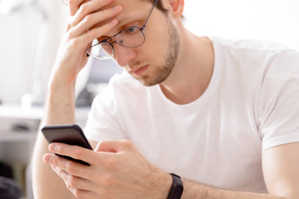 istock Pensive man staring at mobile phone screen holding hand on head 1321285074