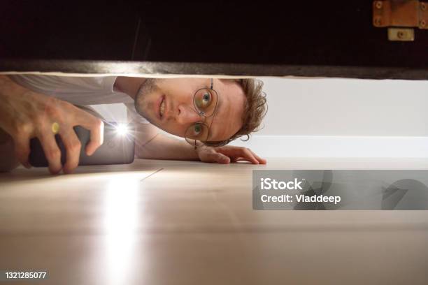 Man With Flashlight Looking Under The Bed Stock Photo - Download Image Now - Searching, Below, Bed - Furniture