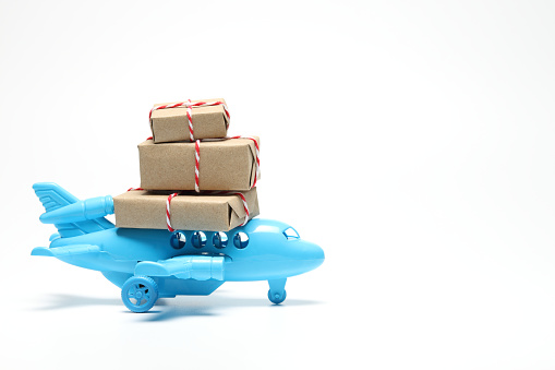 Parcel box on toy airplane in white background with copy space. Air cargo and parcels transportation concept. Fast delivery of goods and products.