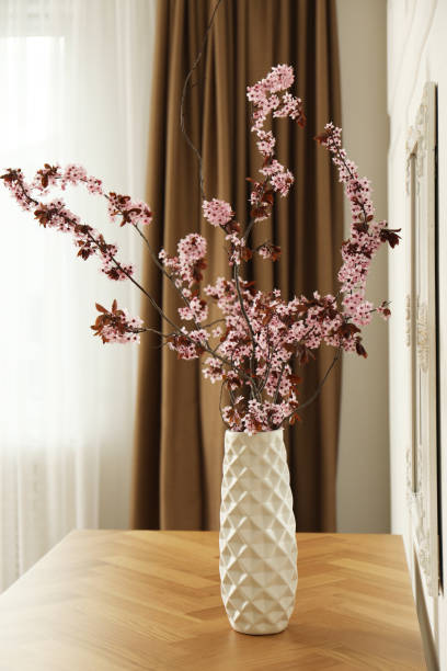 istock Blossoming tree twigs in vase on wooden table indoors 1321287156