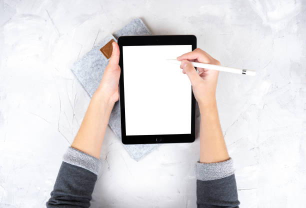 istock Female using a digital tablet and a stylus pencil on a light concrete background 1321290018