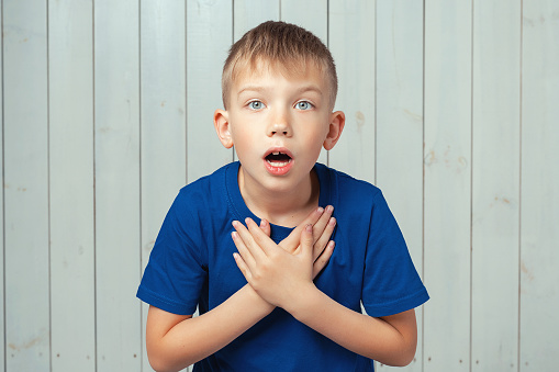 Wow, I canT believe this. Portrait of astonished preteen boy in blue t shirt with stunned shocked face. Studio shot, light wooden background