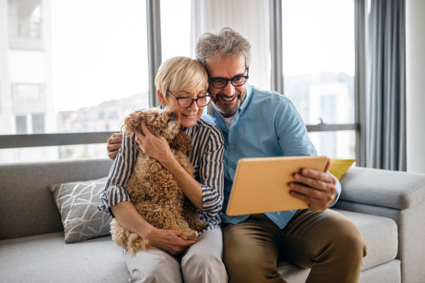 istock Lovely smiling mature couple having fun while using tablet at home 1321294895