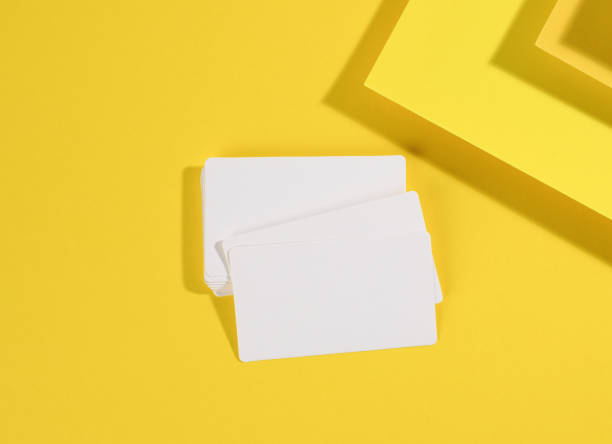 istock blank white rectangular business card on creative yellow background from sheets of paper with shadow 1321295028