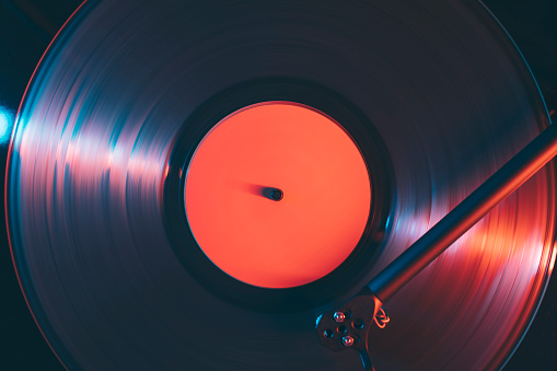 Close up of turntable with gramophone vinyl record playing music at night club.