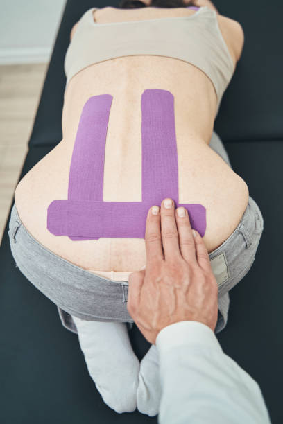 istock Doctor using an elastic therapeutic tape for lower back pain 1321296826