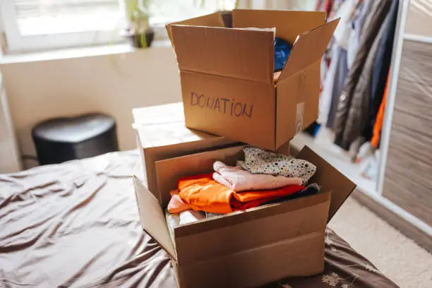 Photo of Boxes with clothes for donation in home interior