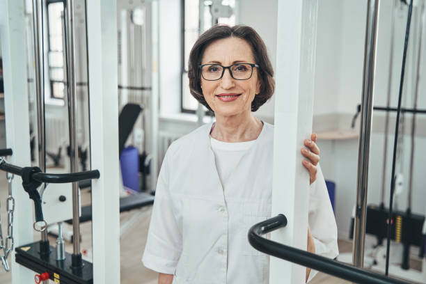 istock Contented physiotherapist in spectacles standing among the exercise equipment 1321297067