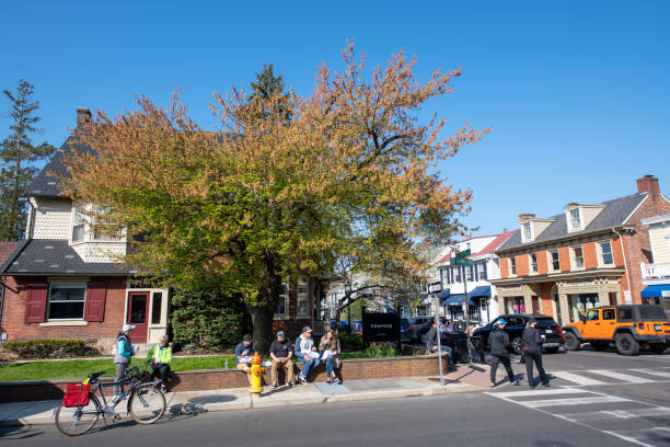 Doylestown, USA - April 24, 2021. Tourists eating or walking on sidewalk in downtown Doylestown, Bucks County, Pennsylvania, USA.