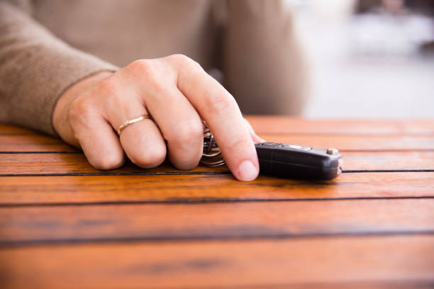 Hands of man holding the car keys with black wallet on wooden table Hands of man holding the car keys with black wallet on wooden table car keys table stock pictures, royalty-free photos & images