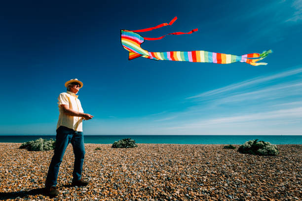 istock Senior man flying colorful rainbow kite at beach 1321299901