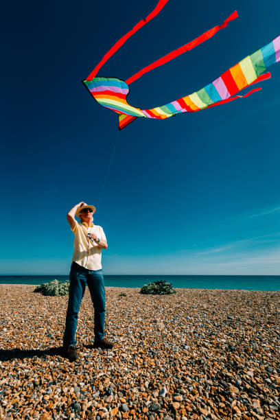istock Senior man flying colorful rainbow kite at beach 1321299925