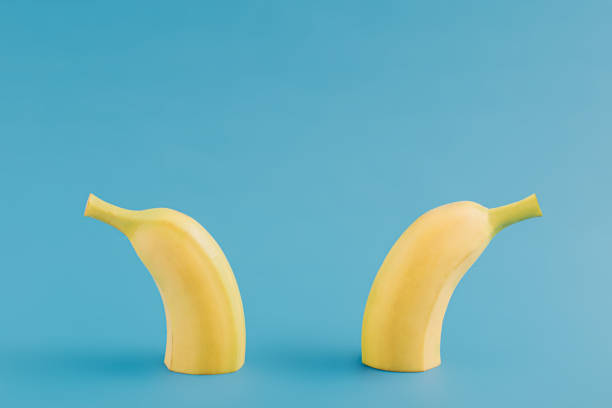 Minimalistic tropical fruit idea with halved fresh organic banana against contrast bright blue background. Creative summer fruit concept, modern creative arrangement.