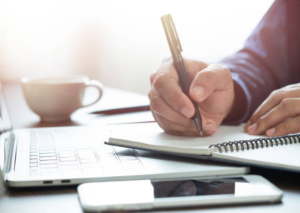 istock man hand using writing pen memo on notebook paper or letter, diary on table desk office. Workplace for student, writer with copy space. business working and learning education concept. 1321302493