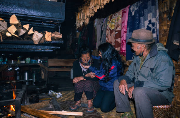 저녁에 음식을 요리하는 화재 장소 근처 자신의 집에서 어린 소녀와 아파타니 부족 부부 - underdeveloped 뉴스 사진 이미지