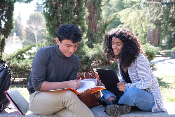 istock Two latin students studying together sitting on a bench outdoors. University life at campus. 1321305102