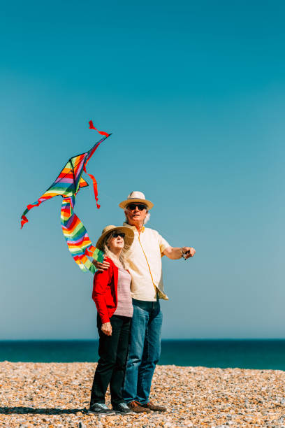 istock Senior couple flying colorful rainbow kite at beach 1321307937