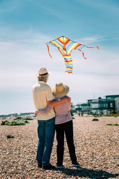 istock Senior couple flying colorful rainbow kite at beach 1321307951
