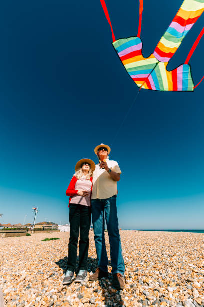 istock Senior couple flying colorful rainbow kite at beach 1321307970