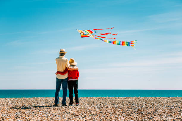 istock Senior couple flying colorful rainbow kite at beach 1321307977